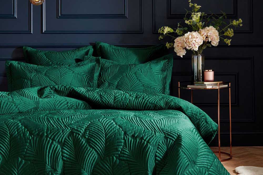 Plush emerald green velvet bedding with a quilter leaf print in a dark painted bedroom - Bold bedding