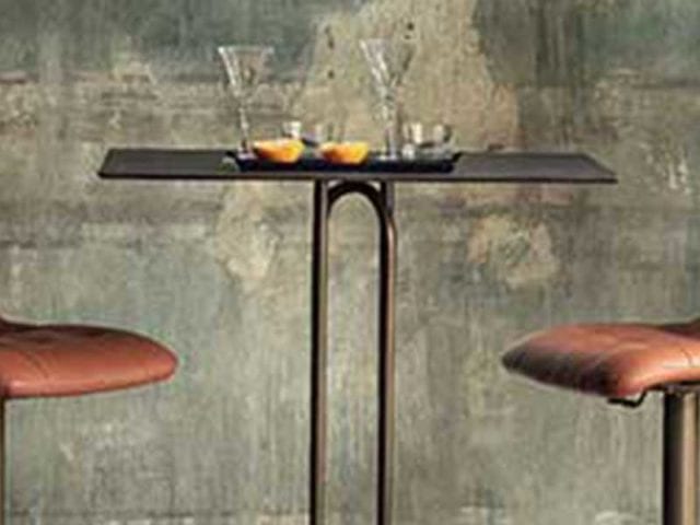 Two brown leather stools with dark brass frames and a tall brass table - Earthy tones - Goodhomesmagazine.com