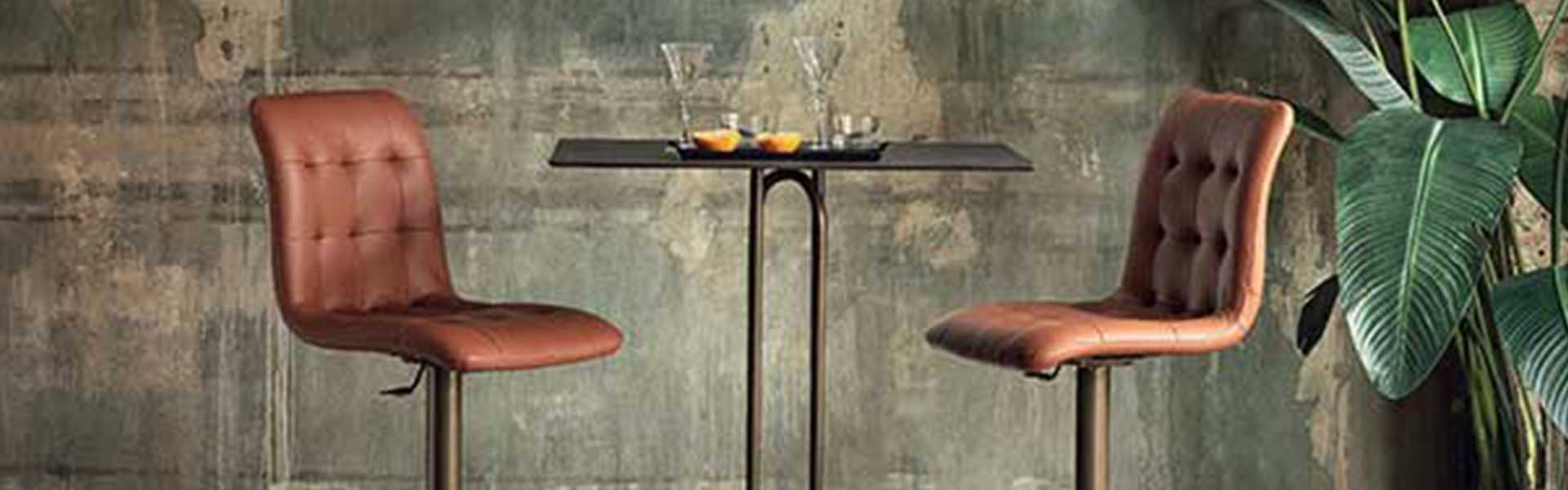 Two brown leather stools with dark brass frames and a tall brass table - Earthy tones - Goodhomesmagazine.com