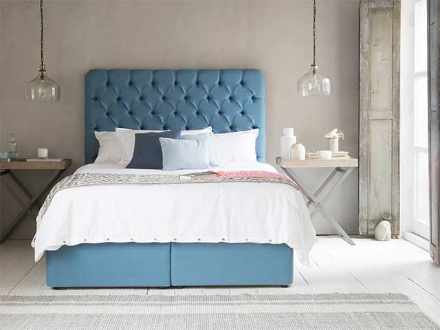 Bedroom featuring a bed with a headboard upholstered in a soft blue fabric - Statement bedroom - Goodhomesmagazine.com