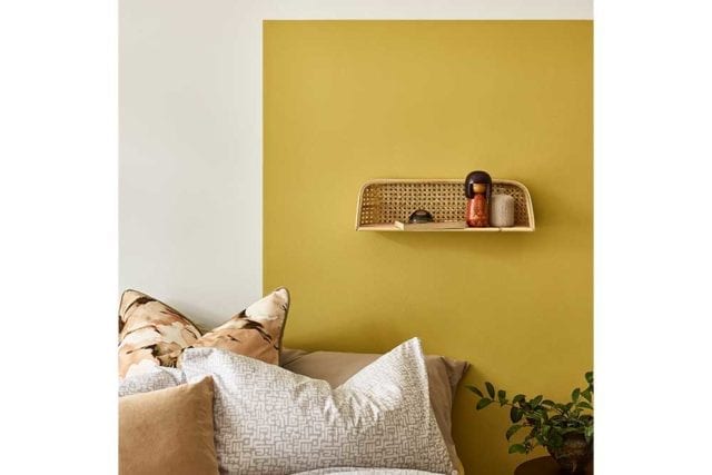 A yellow painted headboard on a plain wall behind a bed - Painted headboard - Goodhomesmagazine.com
