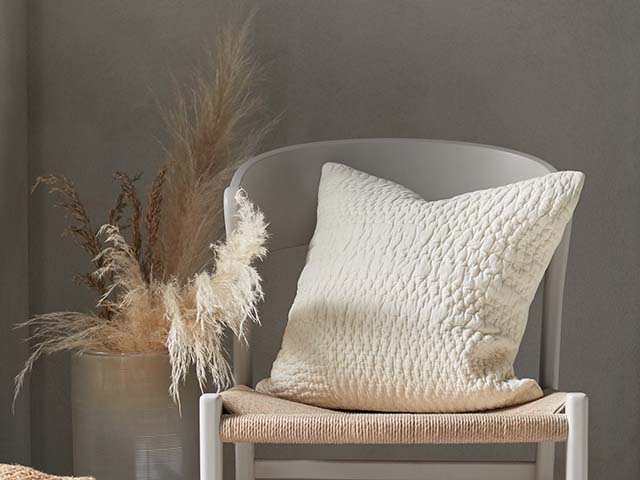 Hand stitched cushion in cream on hard chair - Goodhomesmagazine.com