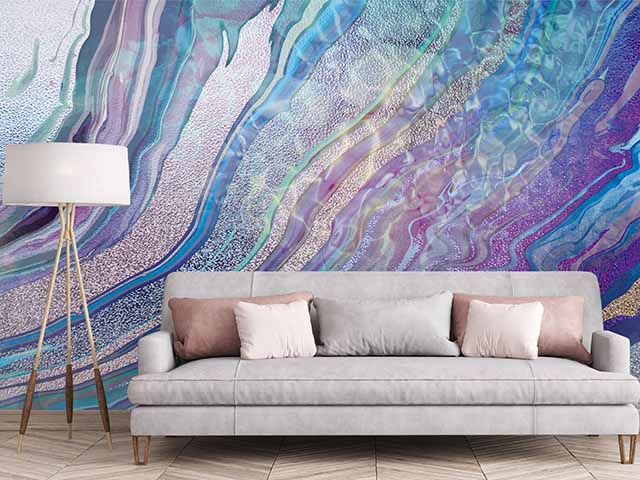 Lilac and blue swirling wallpaper in living room with grey sofa and lamp - Goodhomesmagazine.com