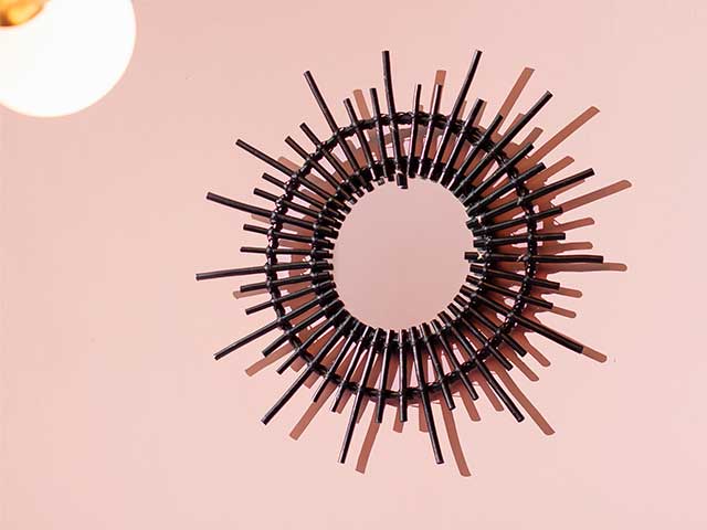 Black spiky rattan mirror on a pink wall - Rattan - Goodhomesmagazine.com