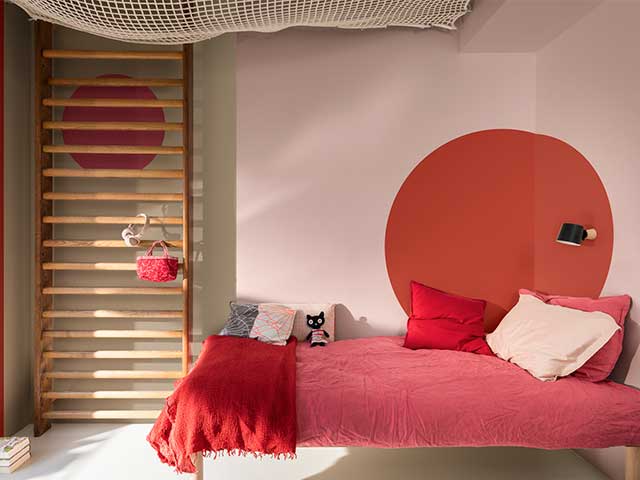 Modern bedroom with pink and red walls, a bed with pink bedding, and red accessories - Statement bedrooms - Goodhomesmagazine.com