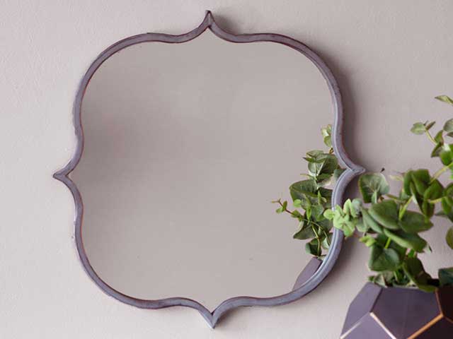 A mirror with curved sides and pointed edges hanging on a wall - Garden mirrors - Goodhomesmagazine.com