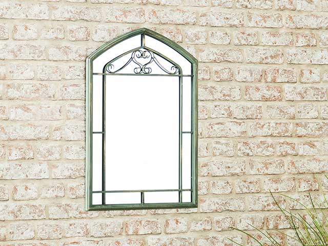 Rectangular shaped mirror with a pointed top, hanging on a briick wall - Garden mirrors - Goodhomesmagazine.com