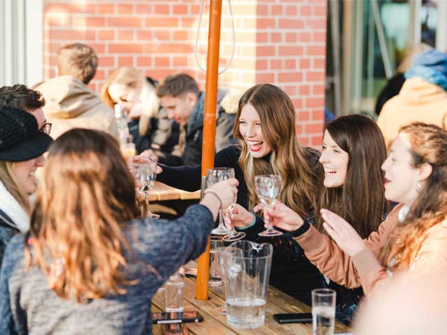 Six people around a picnic table cheersing with their glasses - UK day trips - Goodhomesmagazine.com