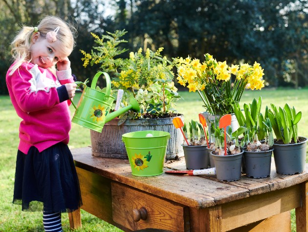 Young girl with an RHS mini watering can tending to plants and flowers