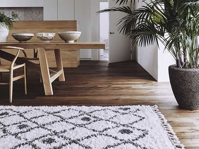 A white fluffy rug with a black Aztec print on dark brown wooden style flooring - 2021 Flooring trends - Goodhomesmagazine.com