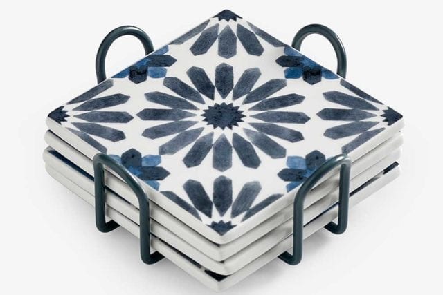 A stack of four white ceramic coasters with a blue Mediterranean tile print - Tile decor trends - Goodhomesmagazine.com