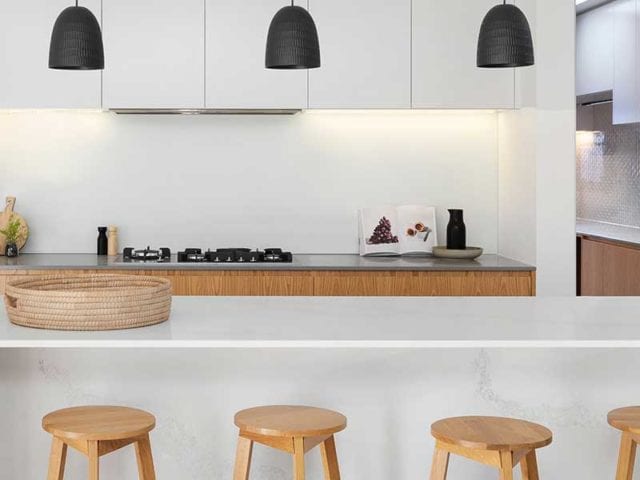Modern kitchen with a white island and four wooden stools - Tiktok kitchen trends - Goodhomesmagazine.com