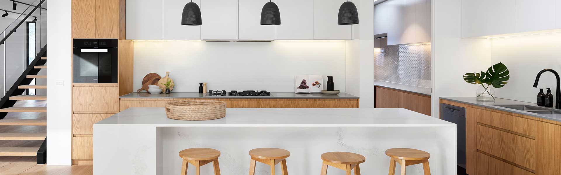 Modern kitchen with a white island and four wooden stools - Tiktok kitchen trends - Goodhomesmagazine.com