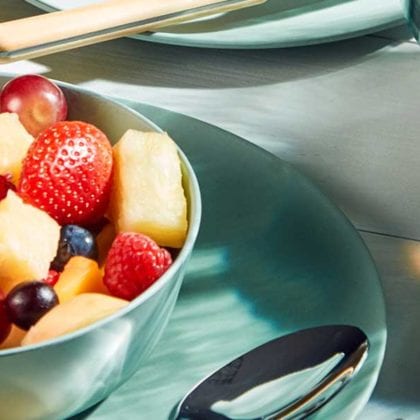 Mint green plate with matching bowl on top of it filled with fruit - BBQ week essentials - Goodhomesmagazine.com