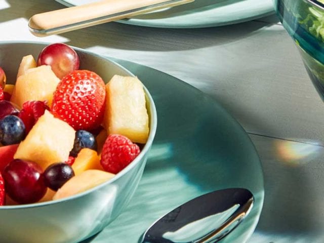 Mint green plate with matching bowl on top of it filled with fruit - BBQ week essentials - Goodhomesmagazine.com