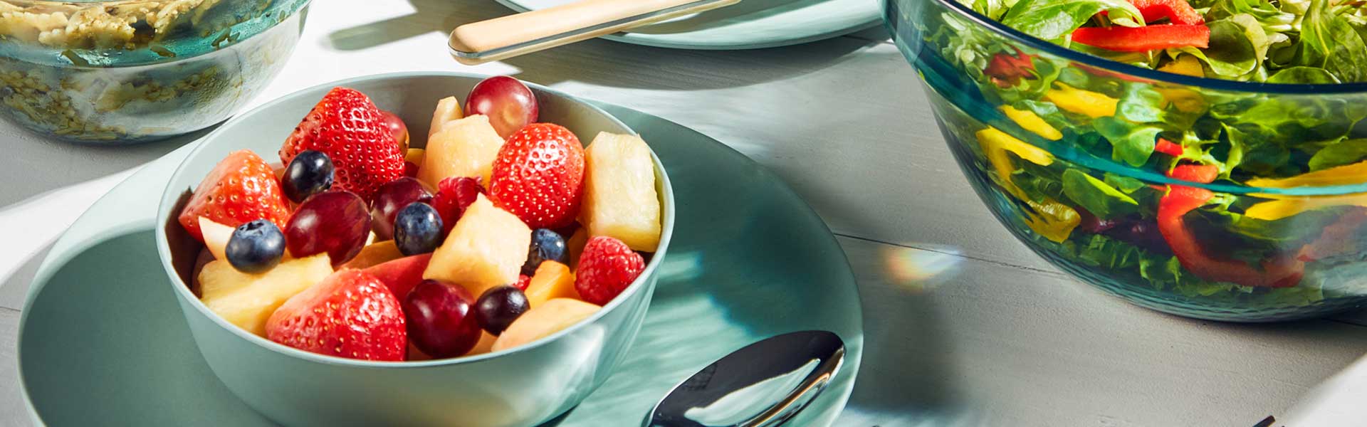 Mint green plate with matching bowl on top of it filled with fruit - BBQ week essentials - Goodhomesmagazine.com