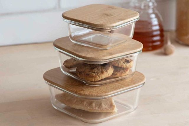 Three stacked different sized glass storage containers with contrasting bamboo lids - Sustainable kitchen swaps - Goodhomesmagazine.com