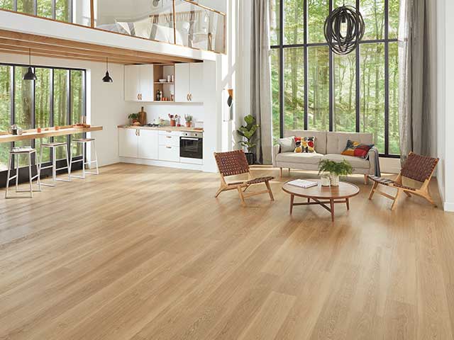 A large room with seating at the far end and a wooden style floor - 2021 Flooring trends - Goodhomesmagazine.com