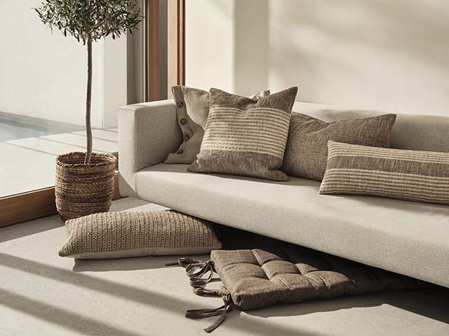 Handmade brown cushions on natural coloured sofa with houseplants, goodhomesmagazine.com