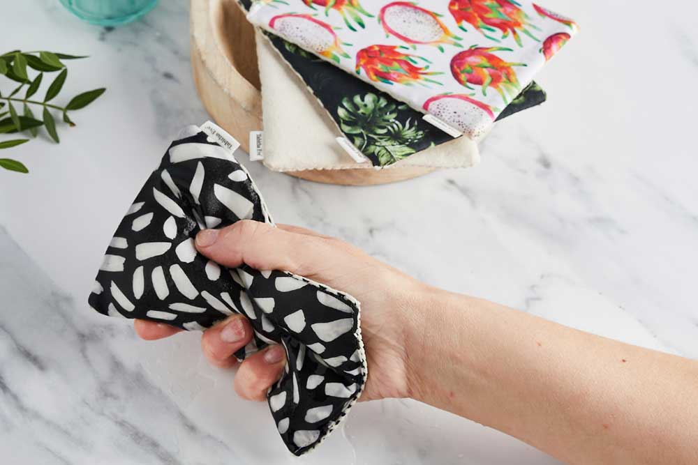 A hand holding a black and white patterned sponge - Sustainable kitchen swaps - Godhomesmagazine.com