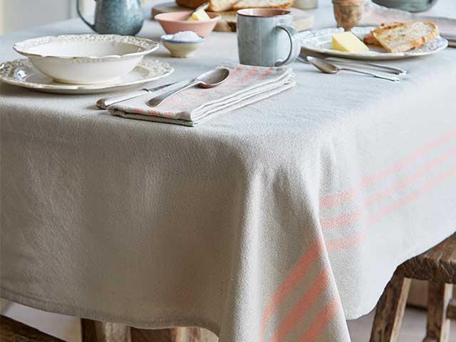 Linen look natural tablecloth with a coral stripe on a table - BBQ week essentials - Goodhomesmagazine.com
