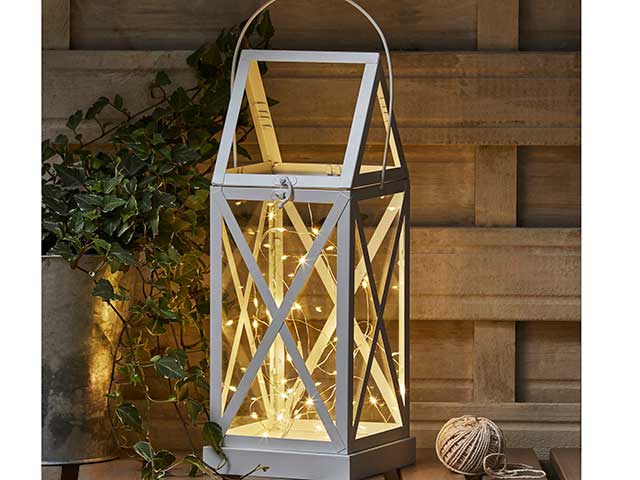 Box lantern with fairy lights inside on wooden background, goodhomesmagazine.com