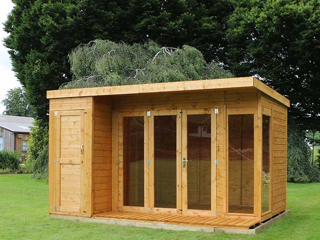  Light wood garden structure with double-glass doors and panels on one size and a shed section too
