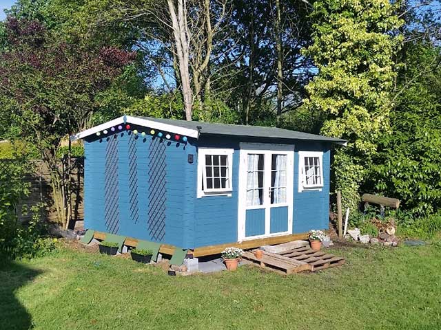 Blue and white large outdoor shed in garden, goodhomesmagazine.com