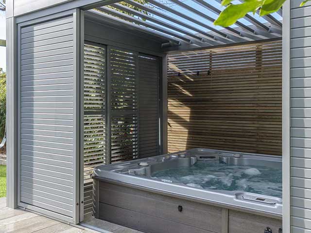 Sleek louvered canopy made from powder-coated aluminium with a hot tub inside