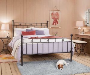 Victorian-style black iron bed frame with a dog on a rug in front of it - Iron beds - Goodhomesmagazine.com