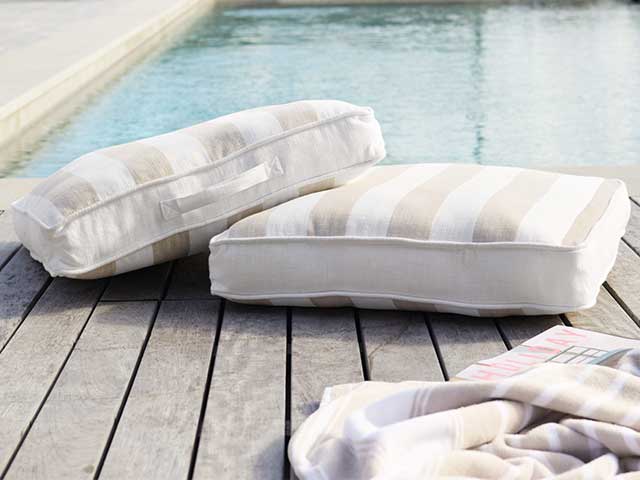 Natural striped floor scatter cushions on some decking next to a swimming pool - Outdoor cinema - Goodhomesmagazine.com