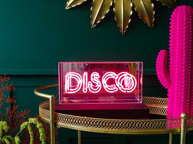 Pink 'Disco' neon light in an acrylic casing on a gold side table - neon lights - Goodhomesmagazine.com