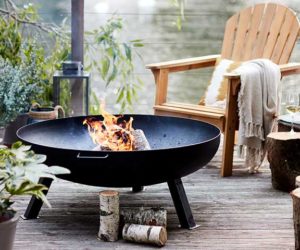 Outdoor open firepit on balcony with wooden chair nearby, goodhomesmagazine.com