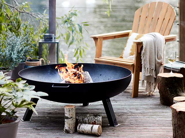 Outdoor open firepit on balcony with wooden chair nearby