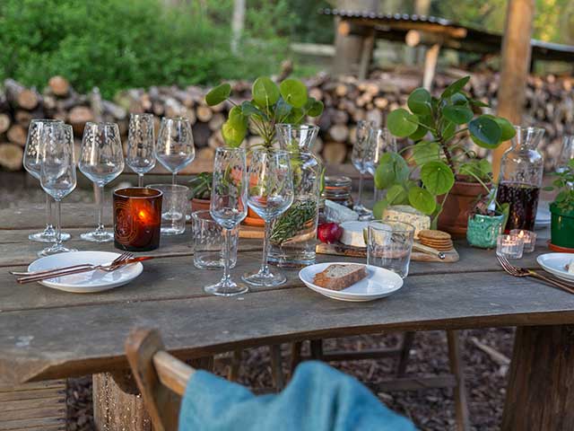 Wine glasses and food on distressed wooden table in outdoor setting, goodhomesmagazine.com