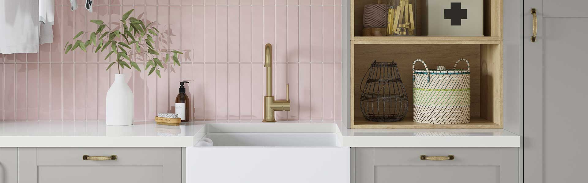 A deep white Belfast sink with a gold tap in front of a pink tiled backsplash - Utility room ideas - Goodhomesmagazine.com