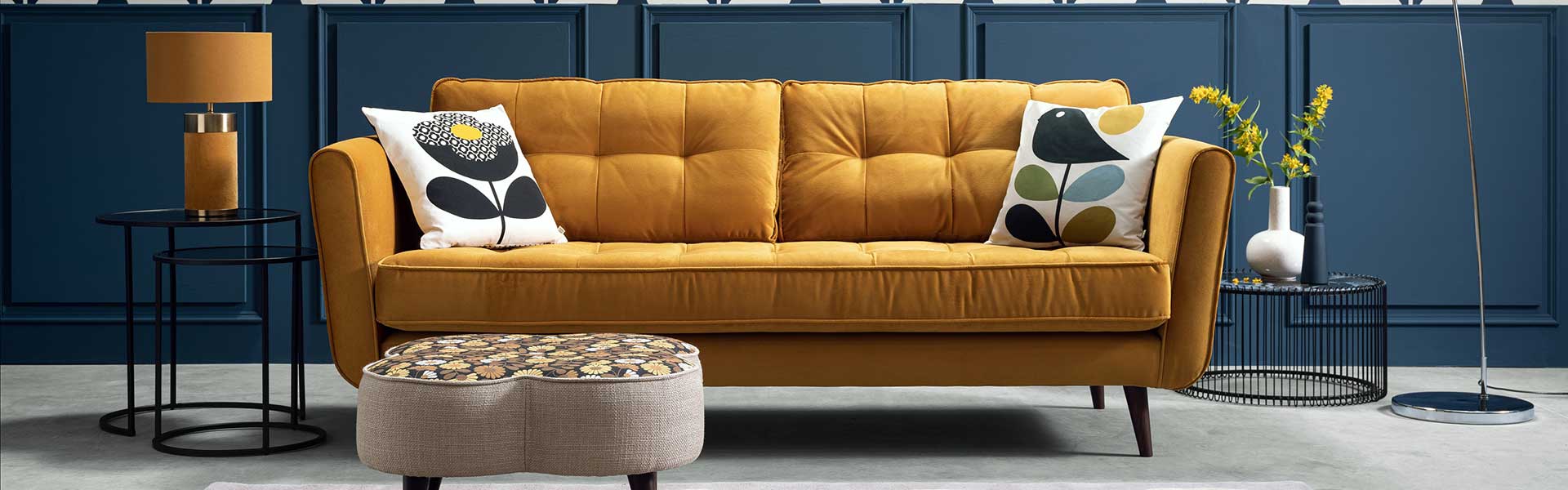 Yellow pincushion sofa with footstll and navy panelled wall behind