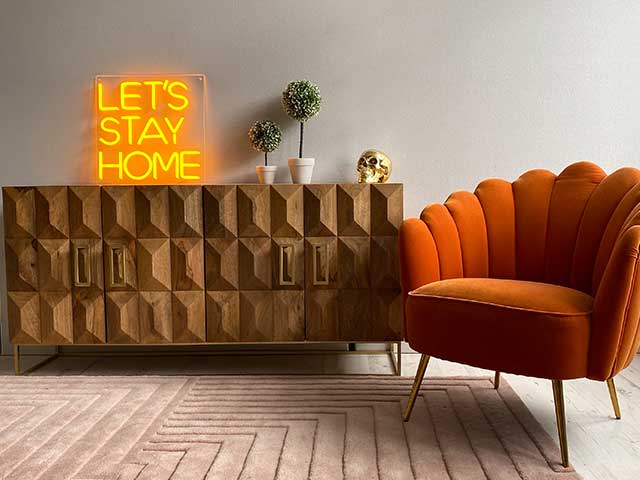 Golden yellow 'Let's Stay Home' neon sign on the wall above a sideboard - neon lights - Goodhomesmagazine.com