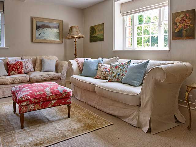 Cream sofas in living space with retro footstool