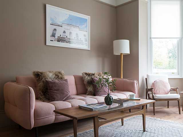 Pink velvet sunken sofa in living room with neutral walls, cream accessories