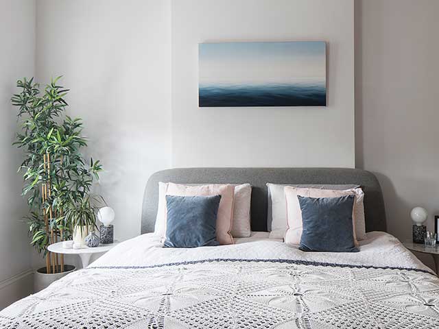 Master bedroom in neutral colours with geometric duvet and green plant