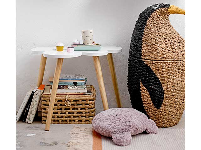 Table with a cloud-shaped top and wooden legs next to a large wicker penguin-shaped basket - Children's bedroom furniture - Goodhomesmagazine.com