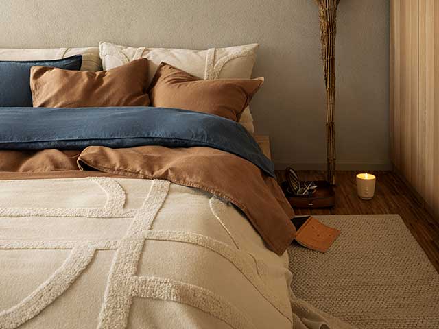 Cream bedding with brown cushions and blankets on wooden floor