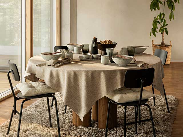 Breakfast table with clear doors and neutral tablecloth, chairs and flooring