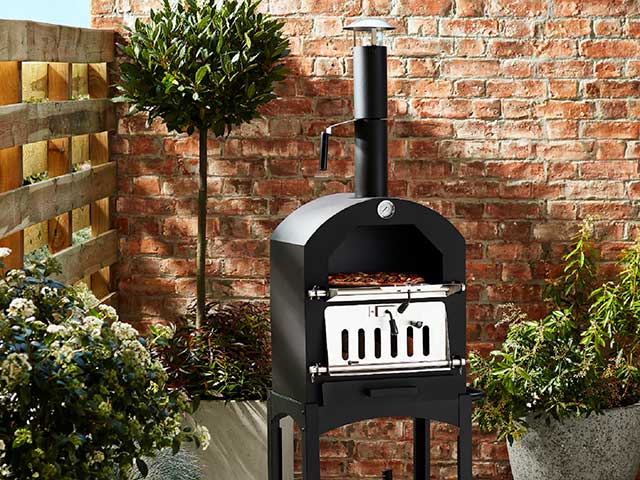 Stonebaked pizza oven against brickwork backdrop with plants