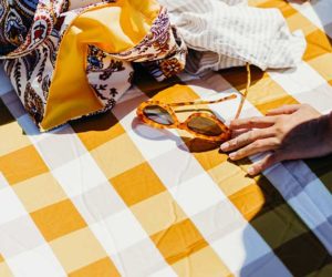 girl sitting on yellow gingham blanket with sunglasses and eco tote
