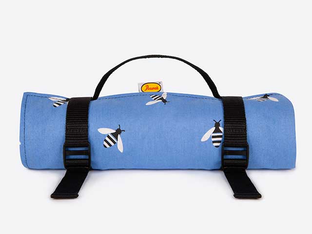 Blue picnic blanket with bees and leather strap on white background