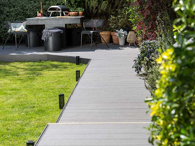 Grey decking pathway surrounding garden and pizza oven