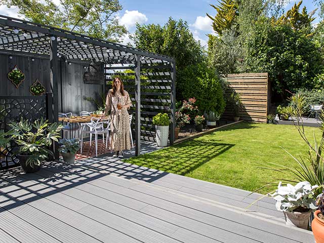 Karen standing in dining outdoor zone underneath pergola overlooking her beautiful garden makeover