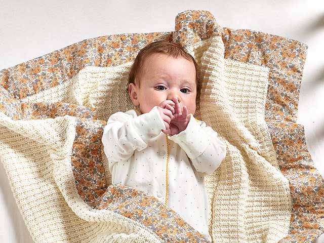 Baby in floral cream blankets from Laura Ashley nursery collection